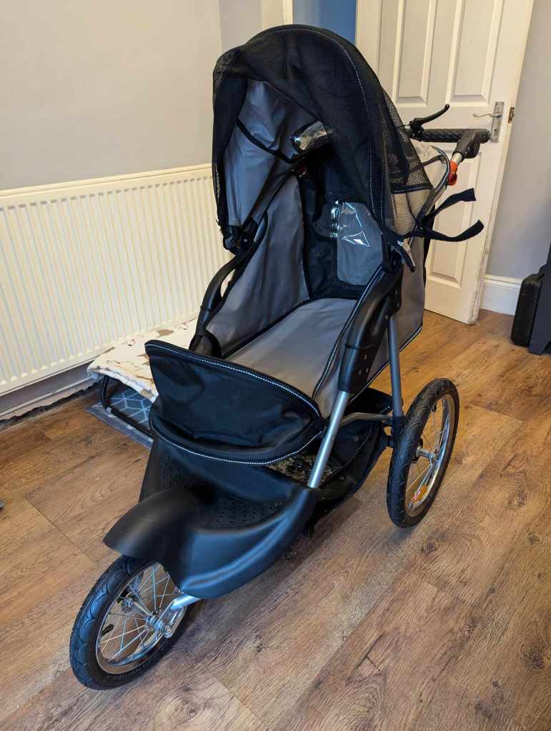 A 3 wheeled, black and grey dog pram